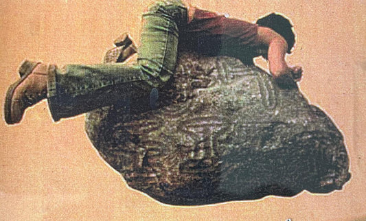 Akutu Irka atop a boulder with a photoshopped image of the carvings mentioned in the story.