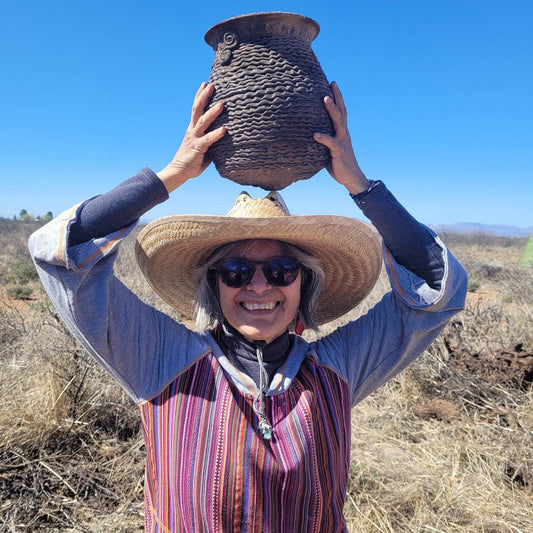Irka Mateo holding a had made clay vase above her head in Santa Fe